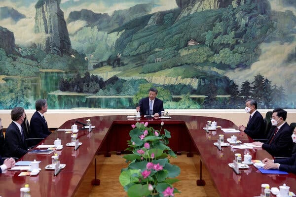 Xi Jinping sits at the end of a long table. Chinese and American officials sit on opposite sides of the table.
