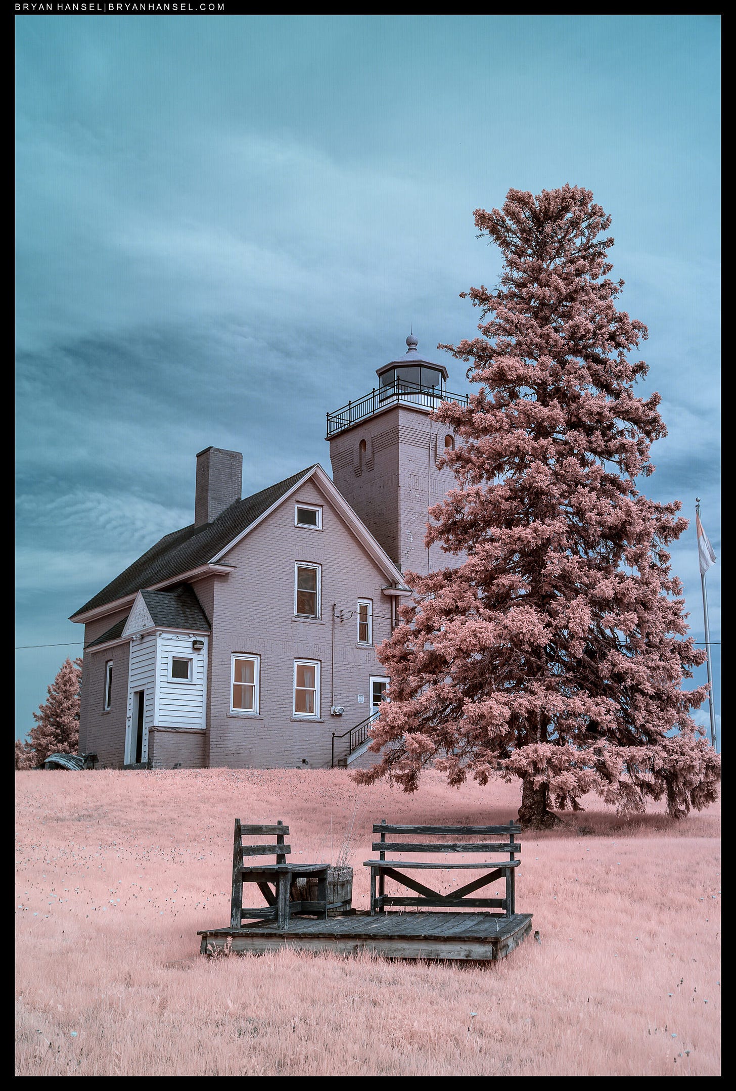 An infrared photo of Two Harbor's lighthouse and a bench in front.