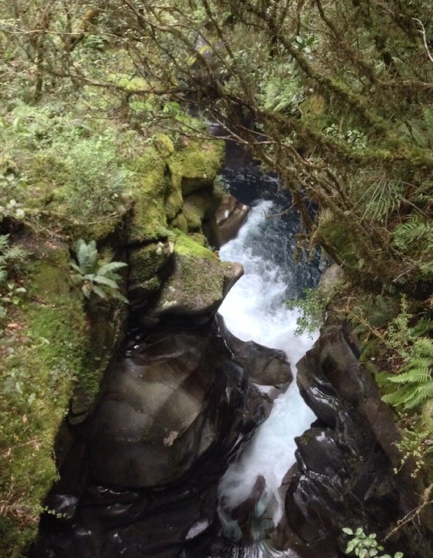 Wet and shiny rocks form a tight gap for water to rush through