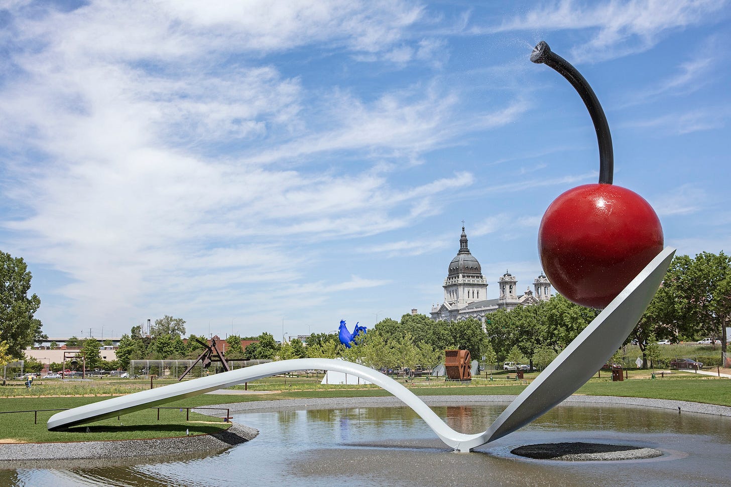 Enormous sculpture of a spoon with a  cherry in its bowl set against the Minneapolis skyline