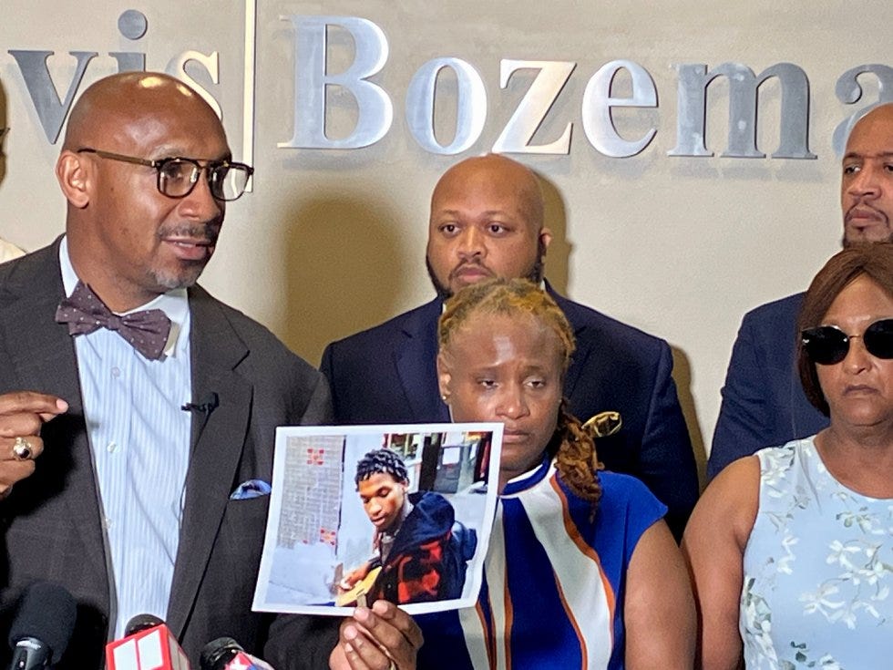 Attorney Mawuli Davi, standing next to the mother of Shawndre Delmore, holds a photo of...