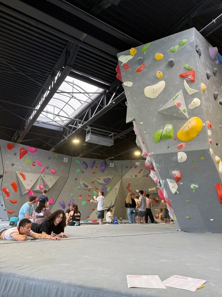 Ascent climbing gym. Several people lounge on the mat.