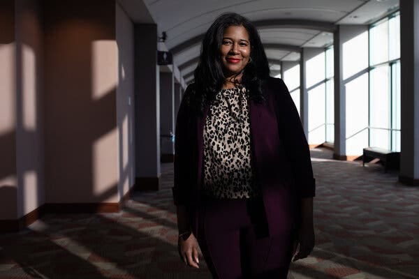 Kristina Karamo, wearing a leopard print shirt under a dark purple blazer, poses for a portrait in a hallway at the state party’s convention.