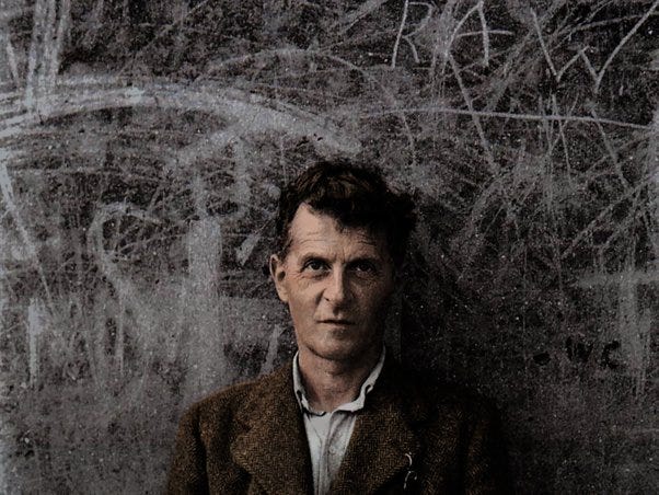 Ludwig Wittgenstein poses in front of a chalkboard.