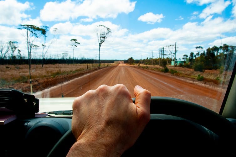 hand on steering wheel with outback scene