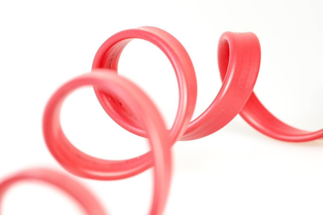 Free Close-up of a red rubber tube with elegant curves against a white background. Stock Photo