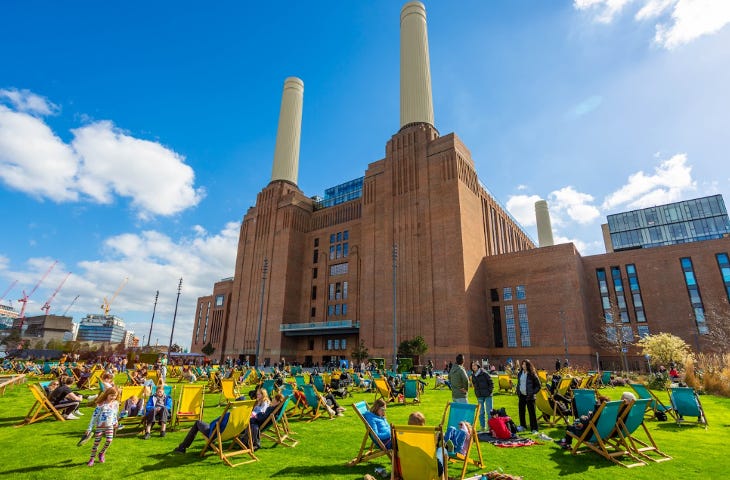 People sitting in deckchairs on the grass outside Battersea Power Station