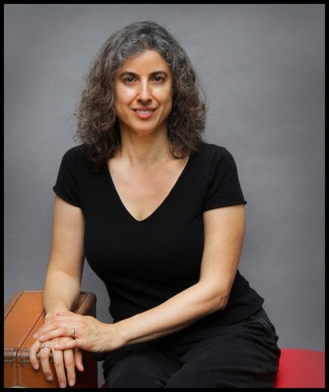 A woman with slightly graying hair in a black V-neck T-shirt