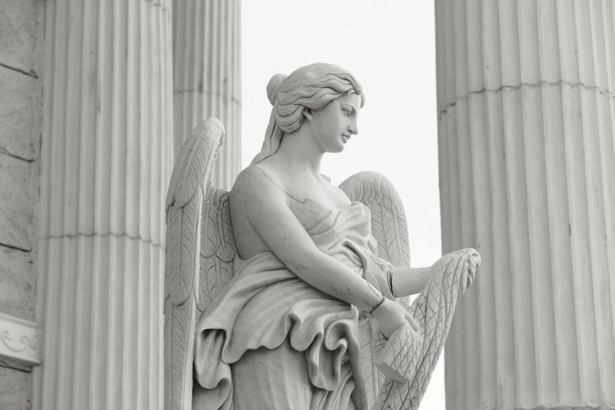 Image of a marble sculpture of a woman with wings, similar to those found in front of government buildings.