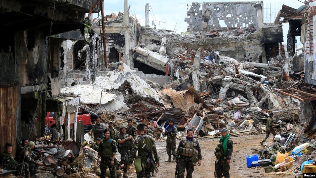 Government soldiers stand in front of damaged houses and buildings in Marawi city, Philippines, Oct. 25, 2017.