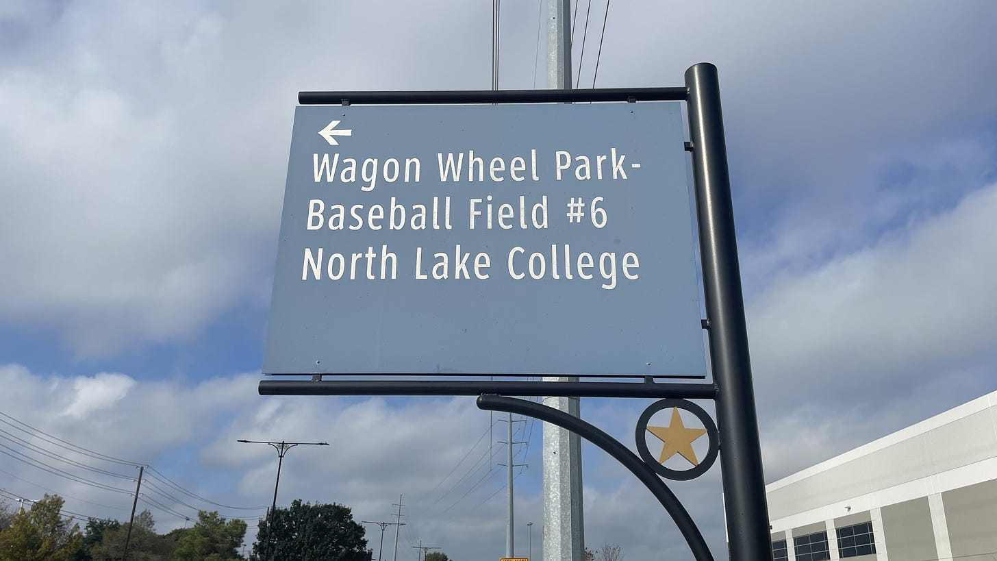 A faded blue sign indicating the locations of a baseball field and community college in Coppell
