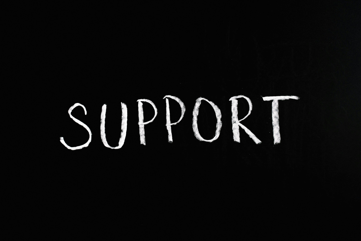 The world “support” written in white chalk on a black background.