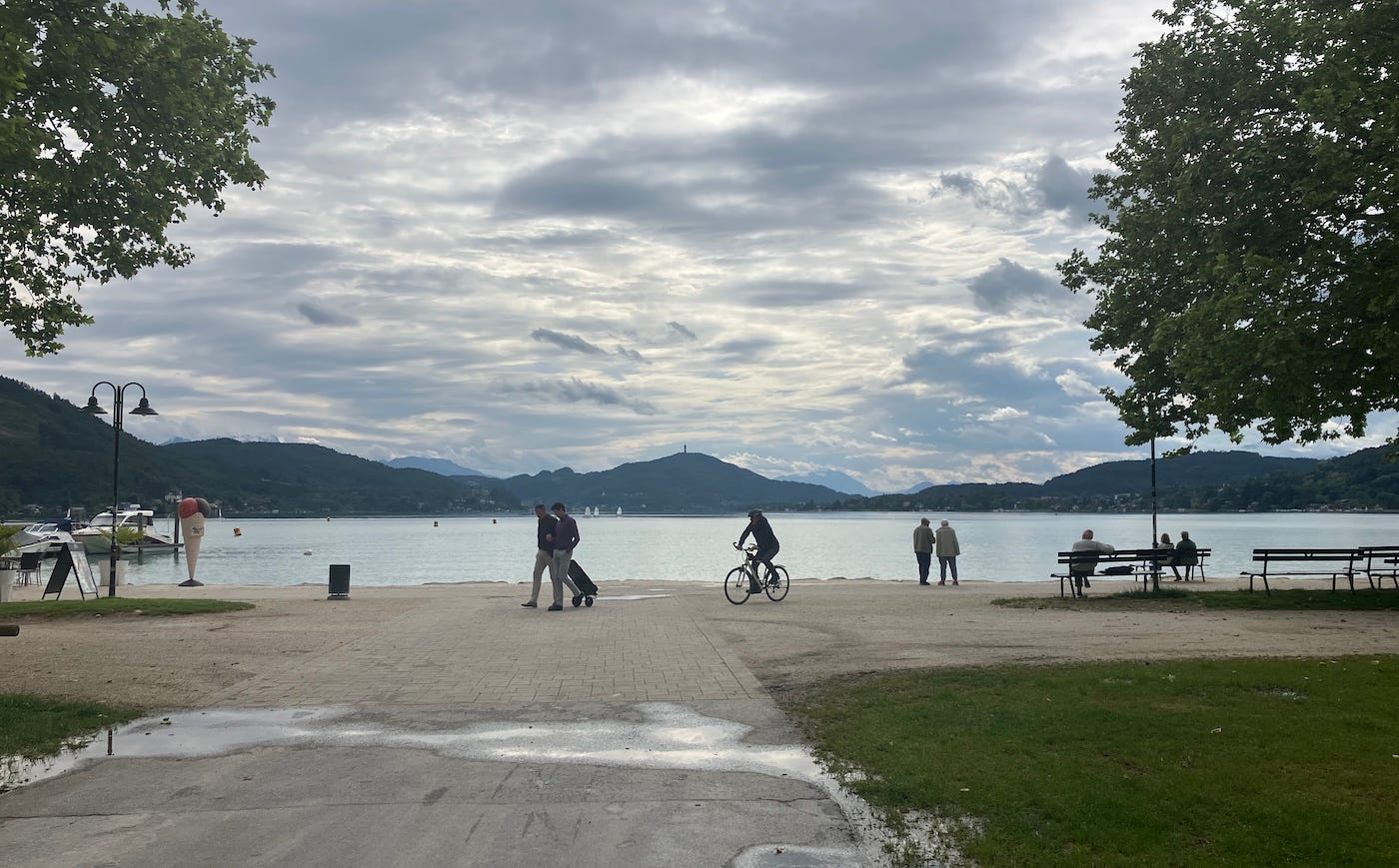 People cycling and walking on the boulevard past the vast lake Wörthersee
