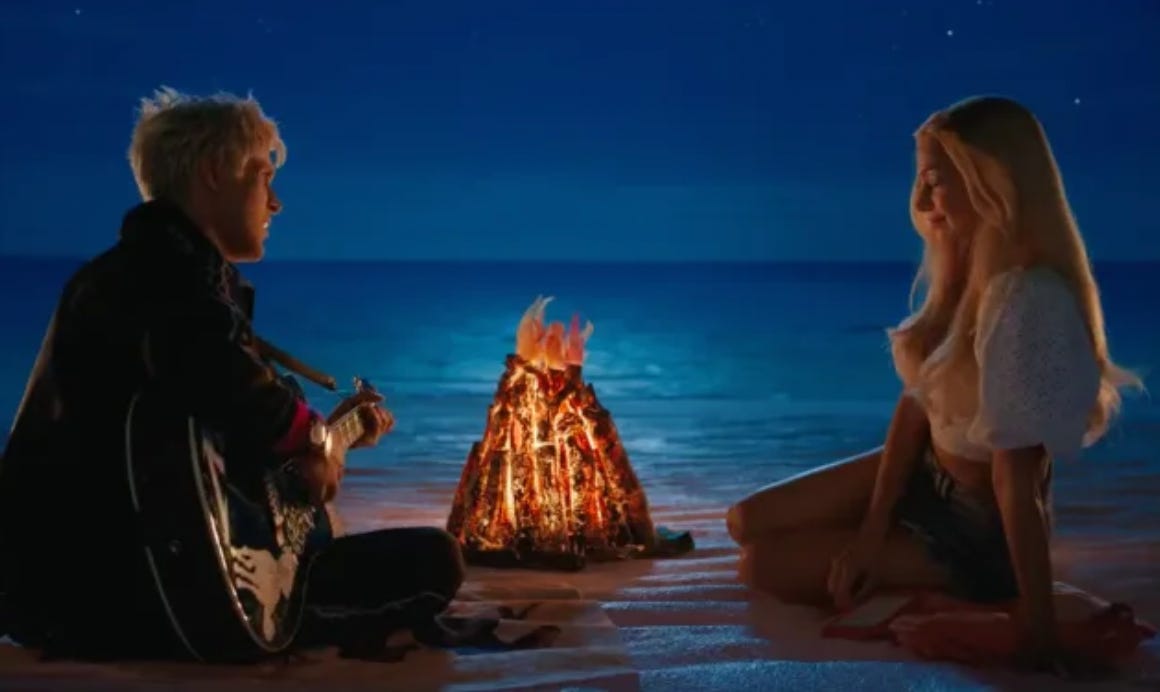 Margot Robbie as Barbie and Ryan Gosling as Ken, sitting on a fake beach at night beside a fake fire. Ken is playing a guitar.