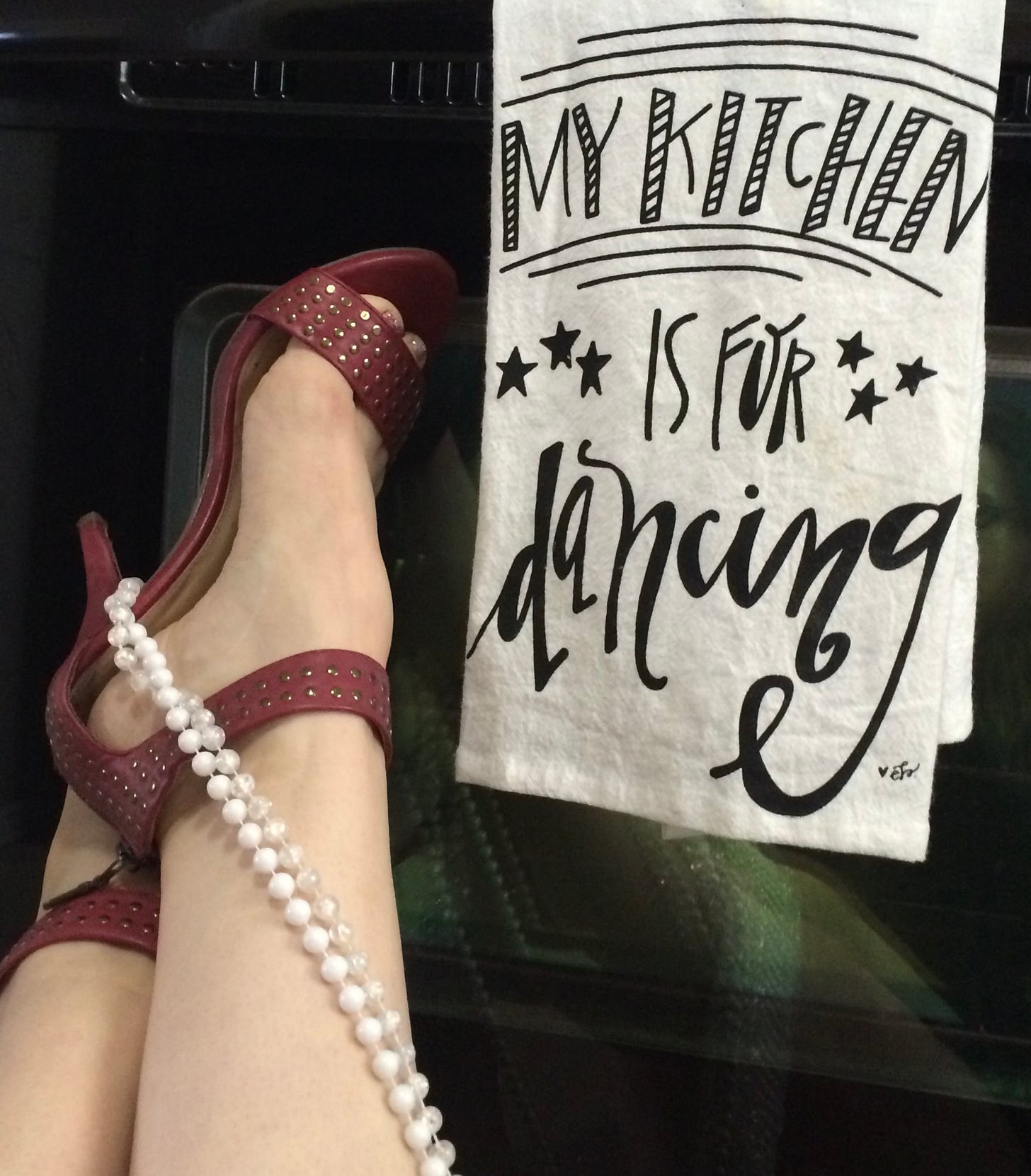 The author's swanky red heels draped in a string of pearls sits propped up against the front of the stove. The towel hanging beside them? "My kitchen is made for dancing."