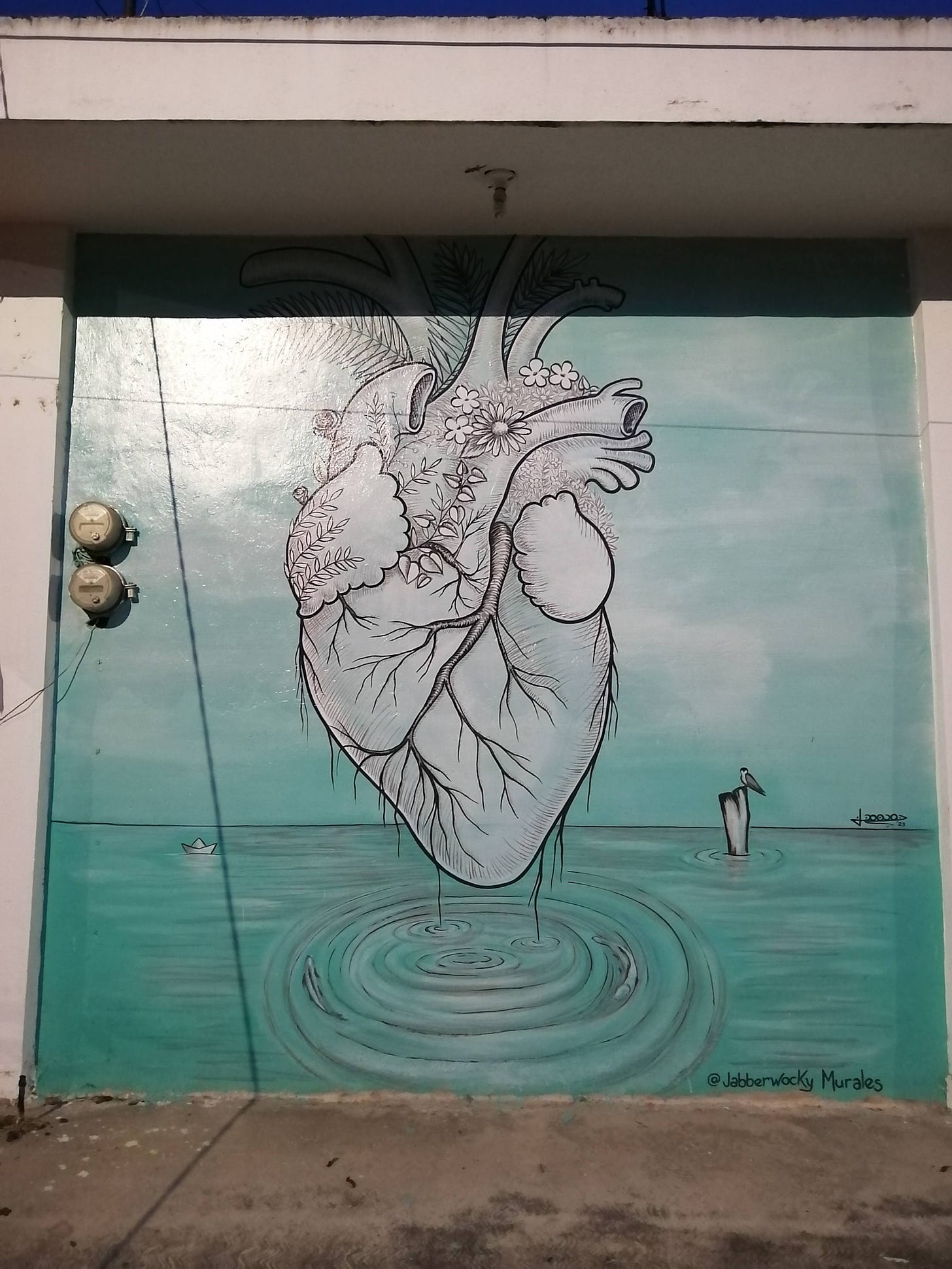 Graffiti of a human heart with leaves and flowers blooming from it. It is hanging over a lake, water dripping into it.