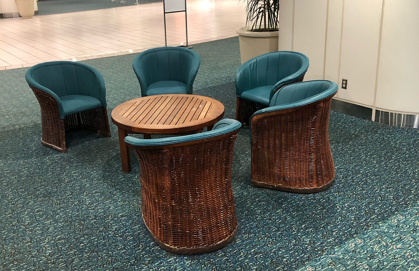 a set of five green wicker chairs surrounding a small wood table