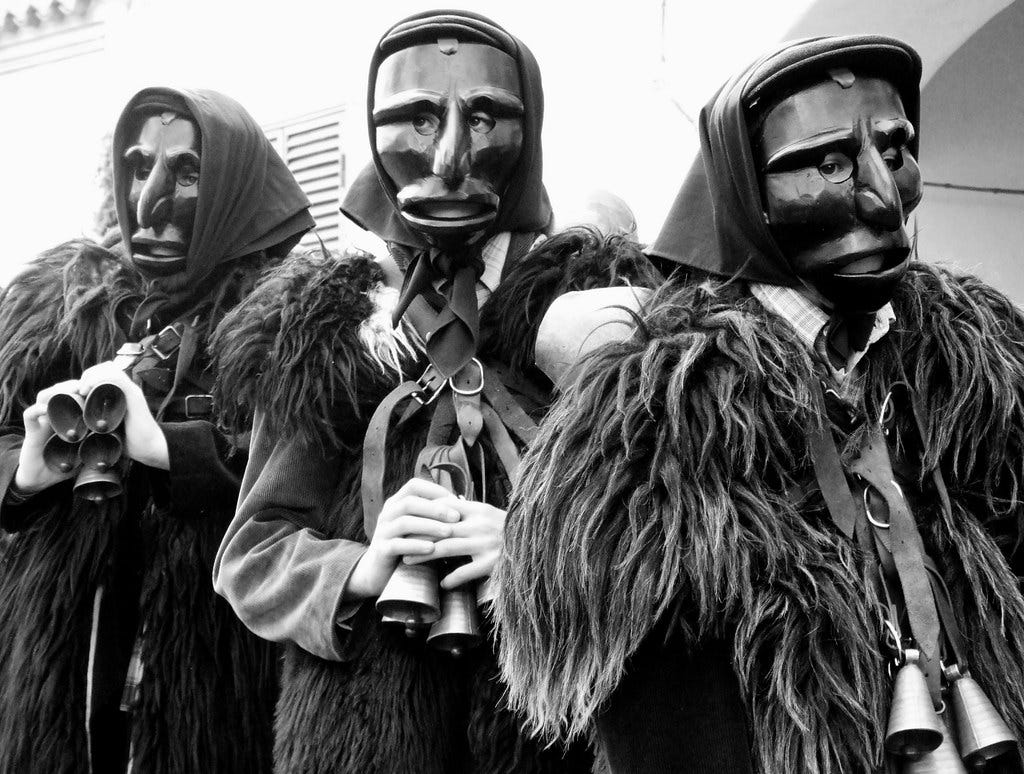 A black and white photo of three Mammuttones, a sardinian carnival mask, waiting for the start of the dance.