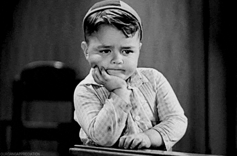 Spanky from the OG Little Rascals: a little boy is sitting at a desk with his hand on his chin and waiting