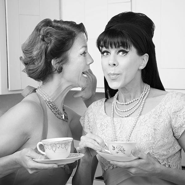 Two women gossiping in the kitchen.