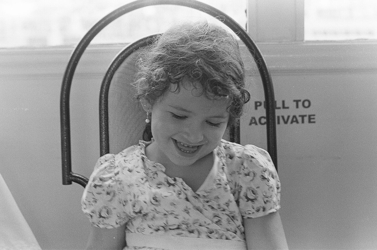 Black and white image of young girl smiling look downward.