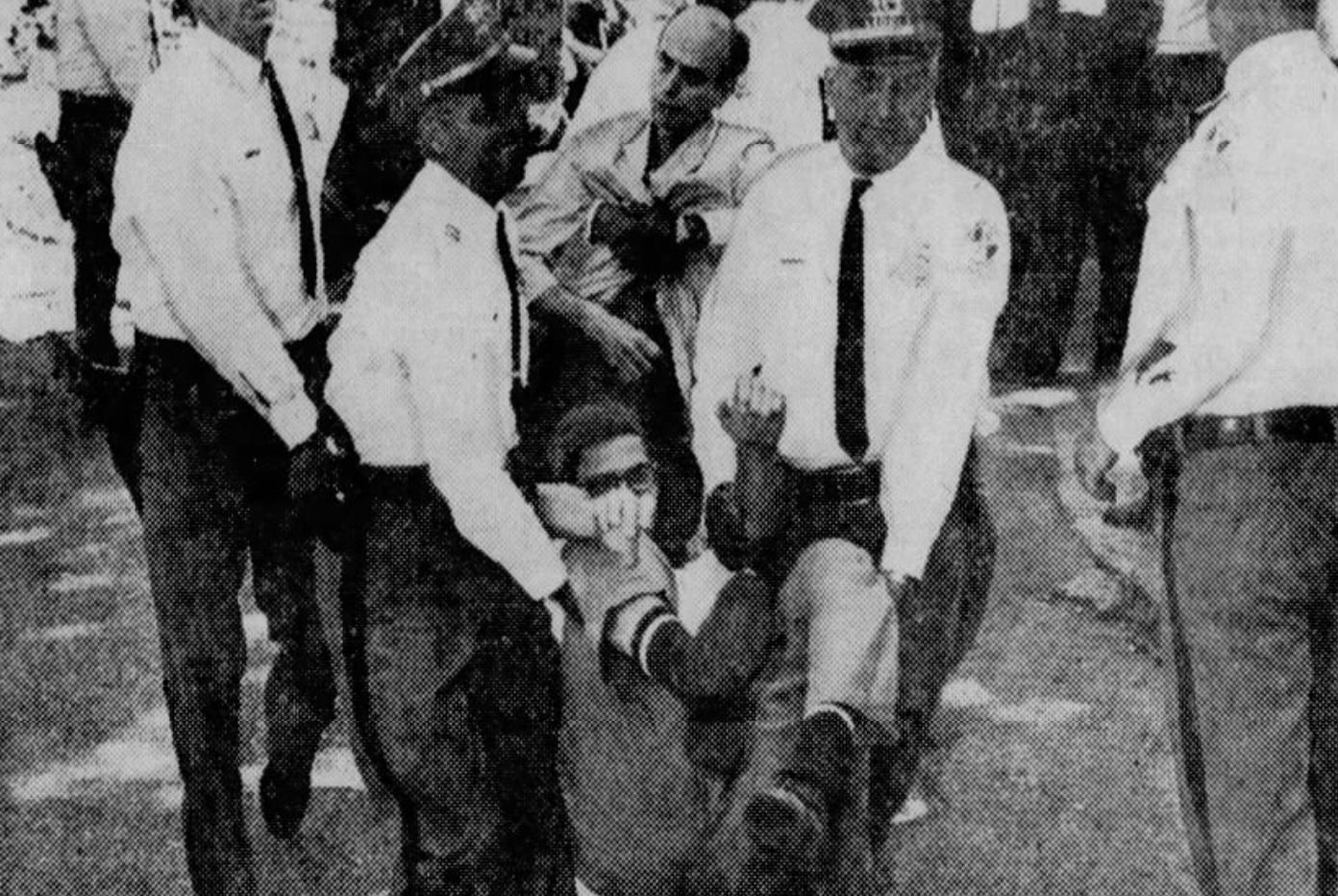 Scanned newspaper photo of two protesters being restrained by the police.