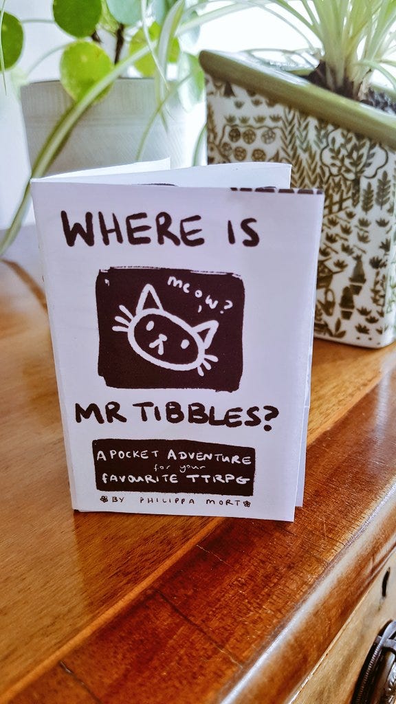 Photo of a small paper zine with the title Where is Mr tibbles, a pocket adventure for your favourite ttrpg, by philippa mort. It has a little illustration of a cat's head saying meow?