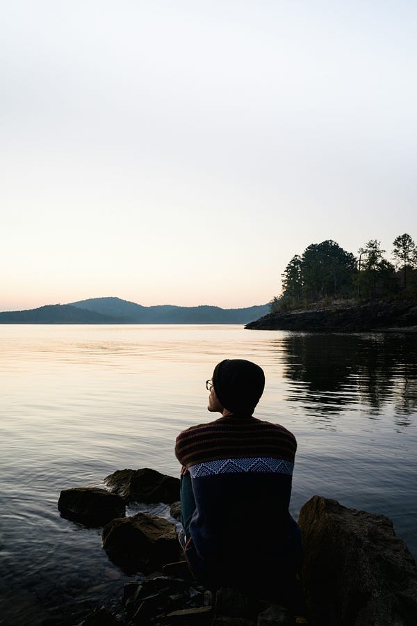 Person sitting at beach looking out at sea. Person sitting at beach looking out at sea.
