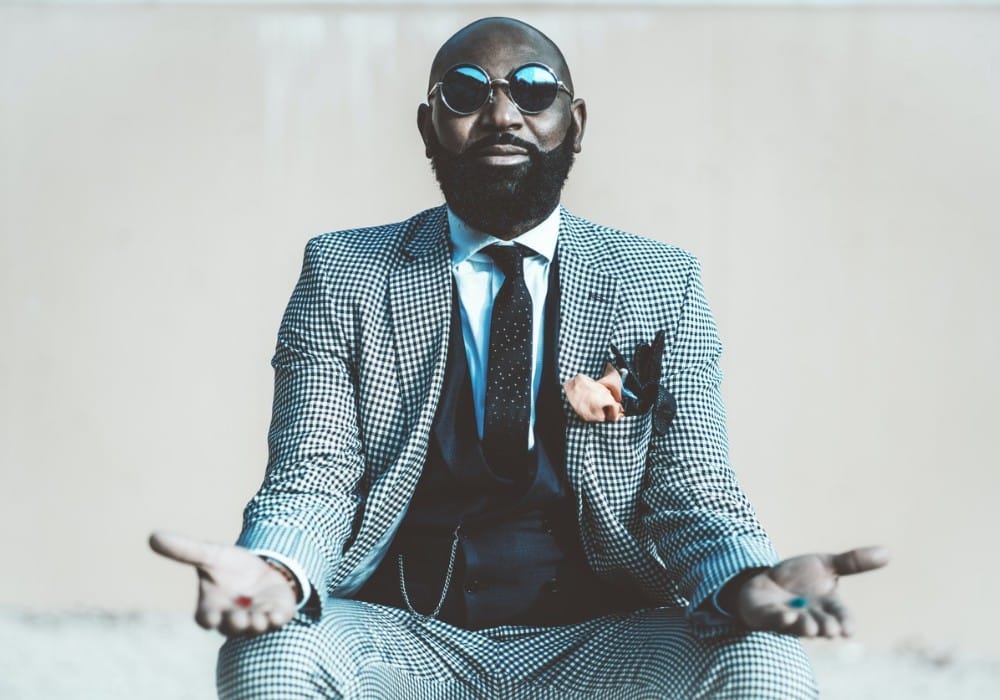 Black man in a suit and sunglasses offering the red pill and the blue pill from The Matrix