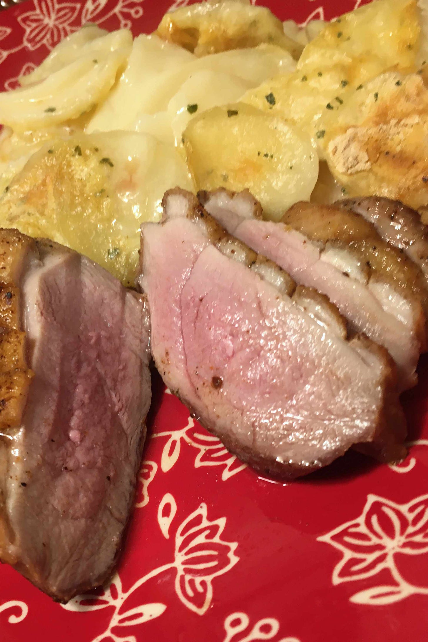 seared duck breast on red plate