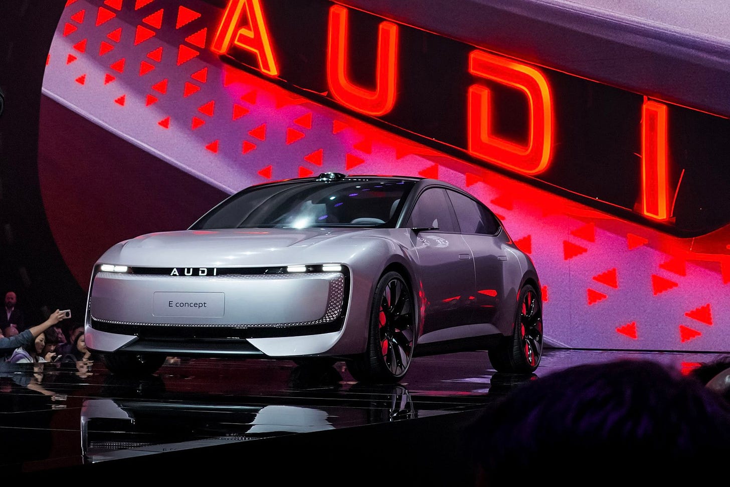 silver car on stage with big all-caps AUDI logo on screen in the back