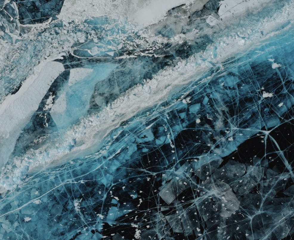 Close-up of frozen water that is blue and white and filled with fractures. 