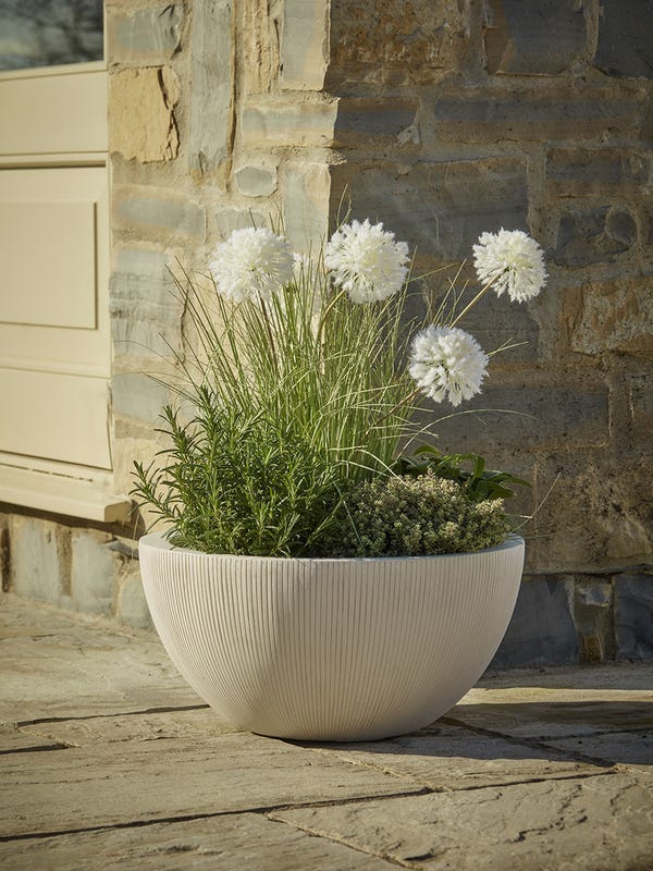 ribber planter in natural stone with white flowers growing