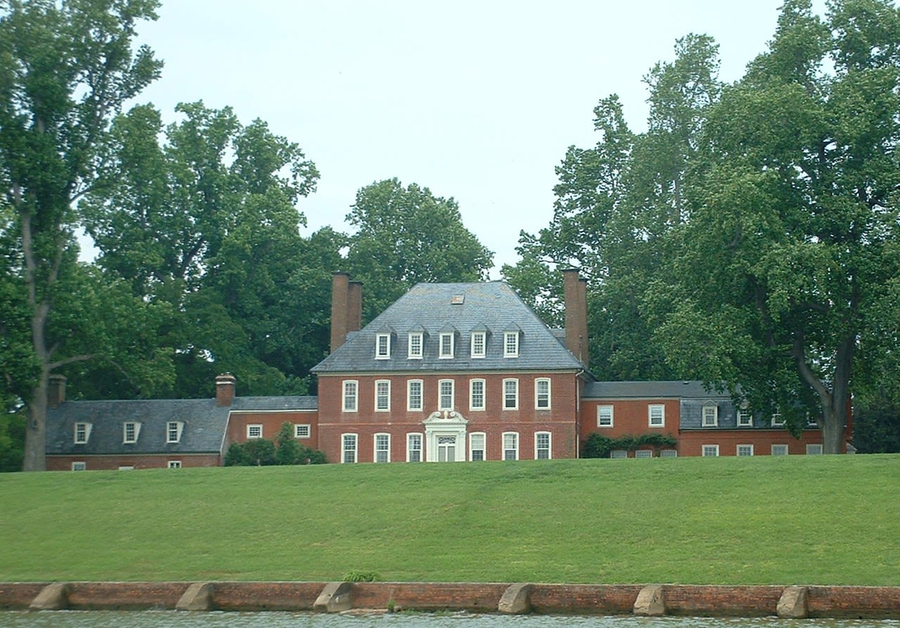 Two story brick house with many windows and two extra wings