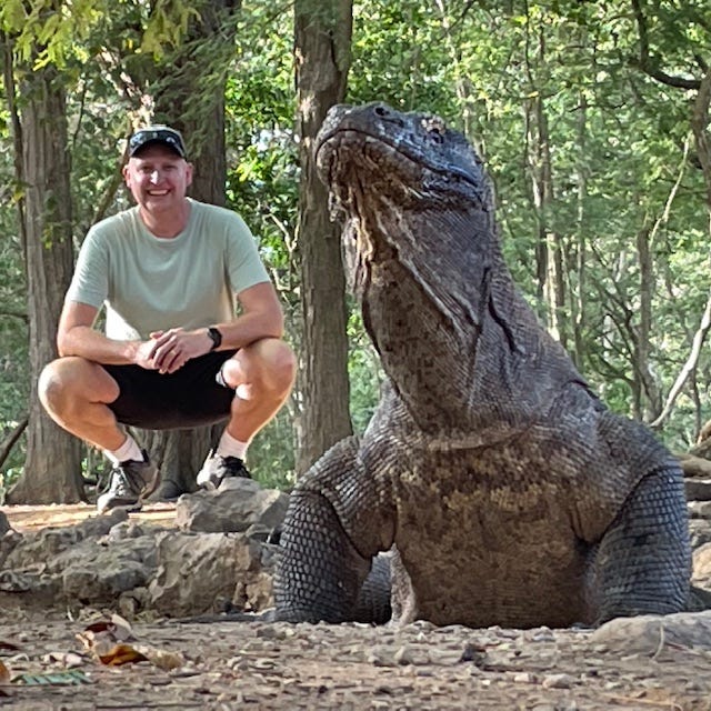 Dr. Dave posing behind a large Komodo dragon