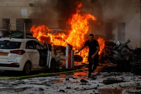 A man runs on a road as fire burns after rockets were launched from the Gaza Strip, in Ashkelon, Israel, on Oct. 7, 2023. (Amir Cohen/Reuters)