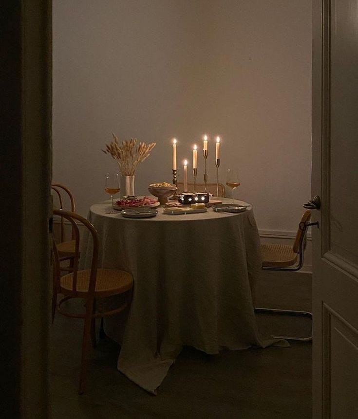 This may contain: a dining room table with candles and food on it in front of the door to another room