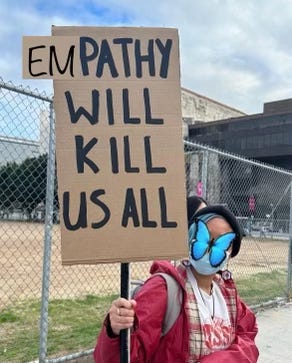 Girl holding sign that says "empathy will kill us all"