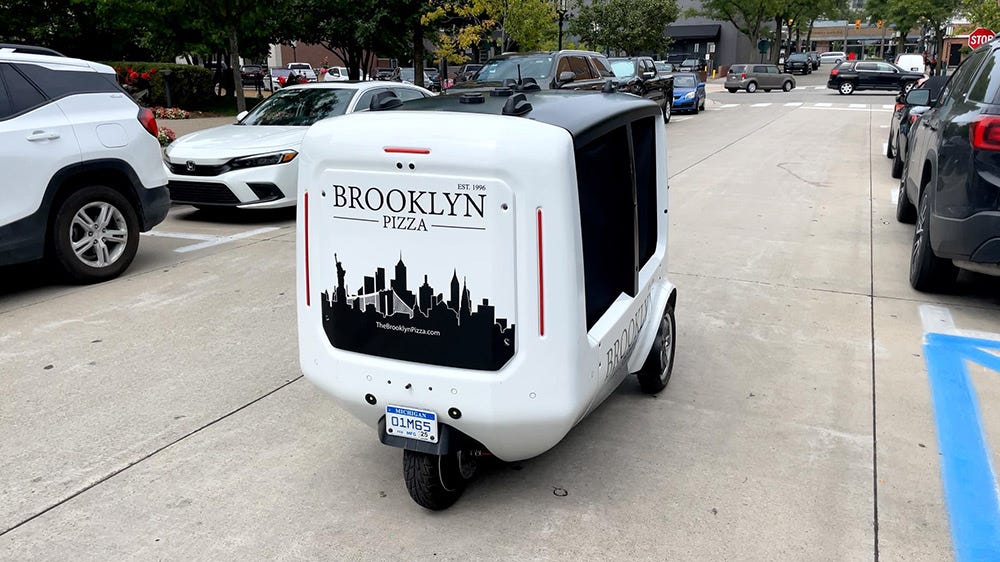 A photo depicting a pizza-delivering robot on a city street