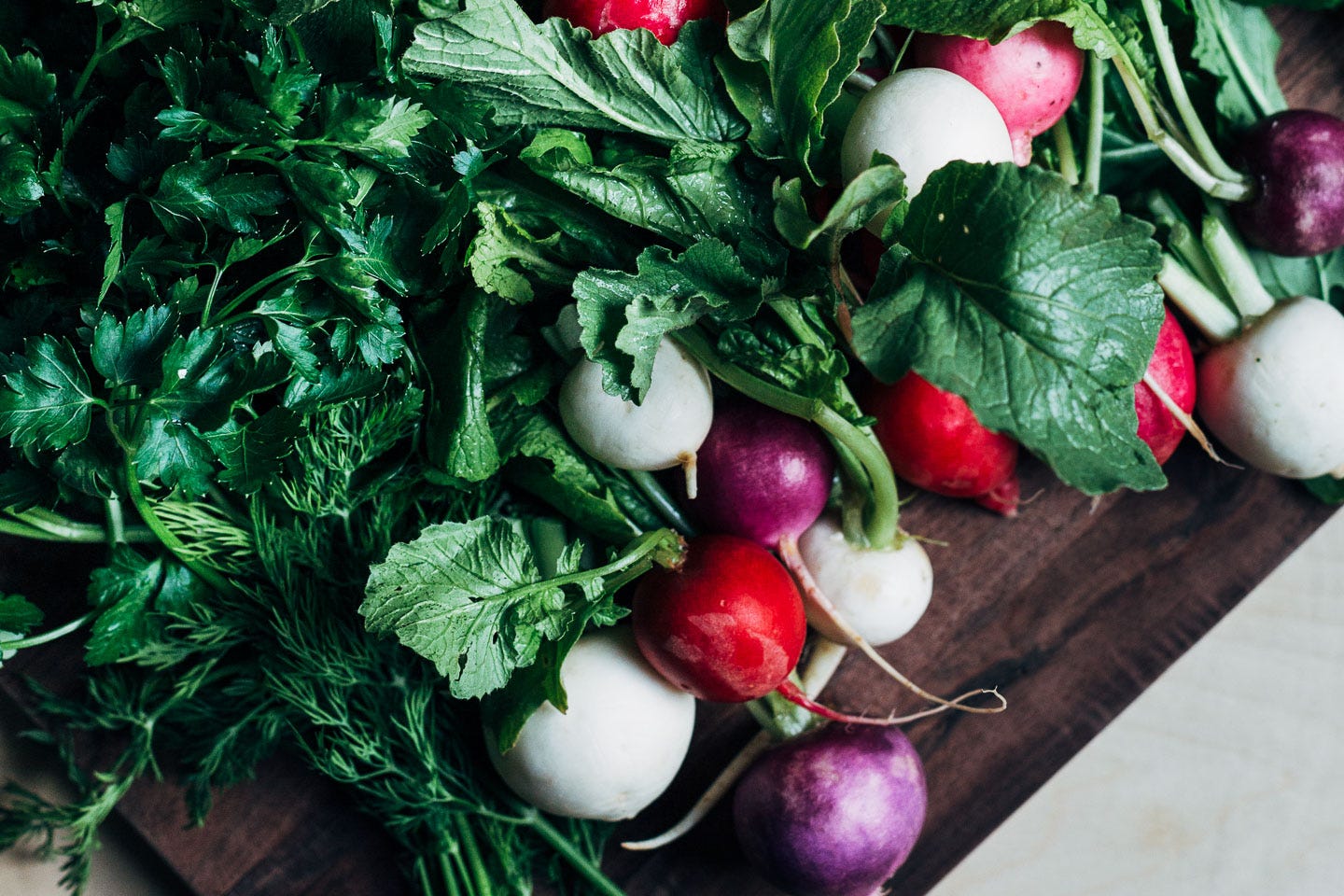Radishes and herbs on a cutting board