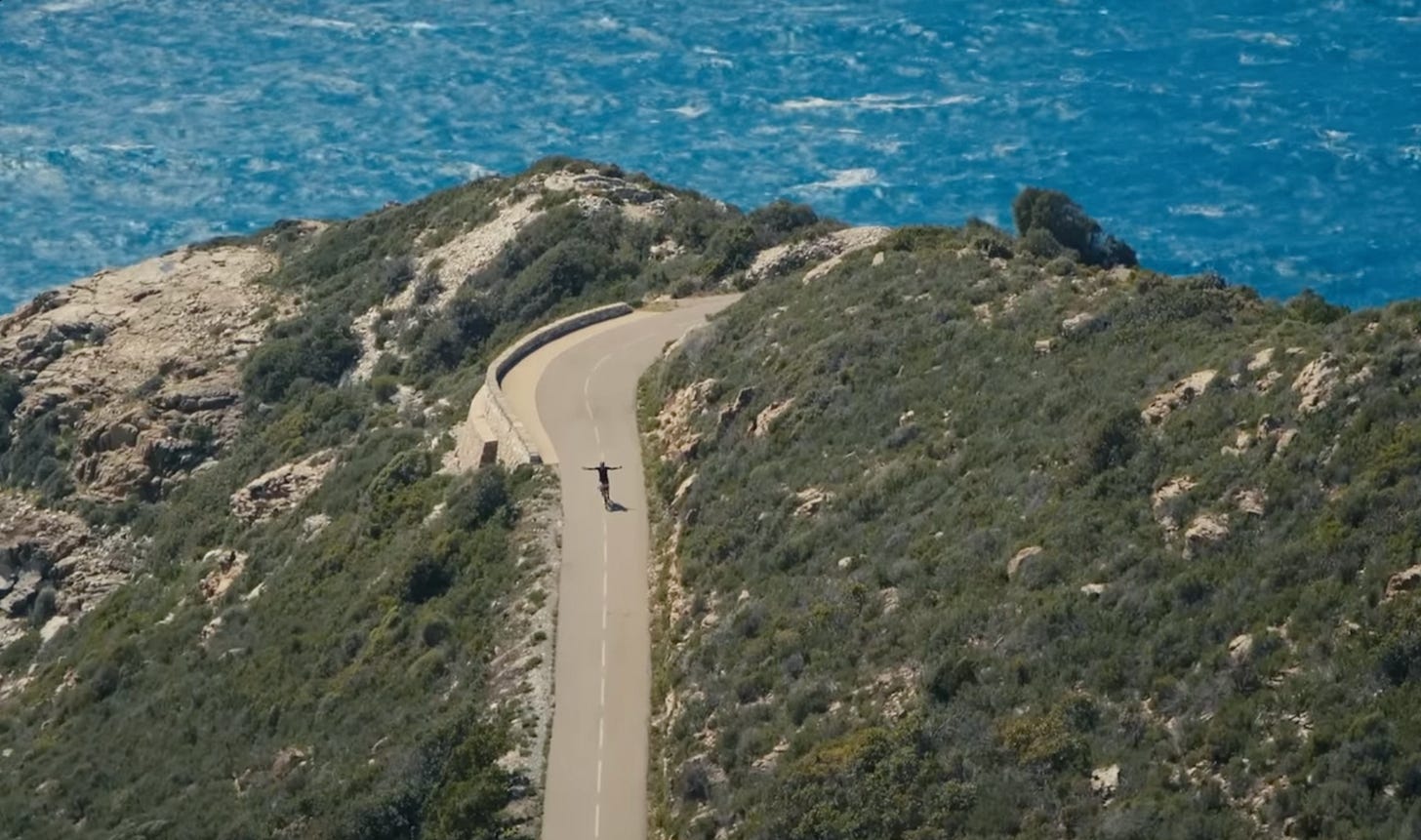 Un cycliste sur une route avec vue la mer derriere lui