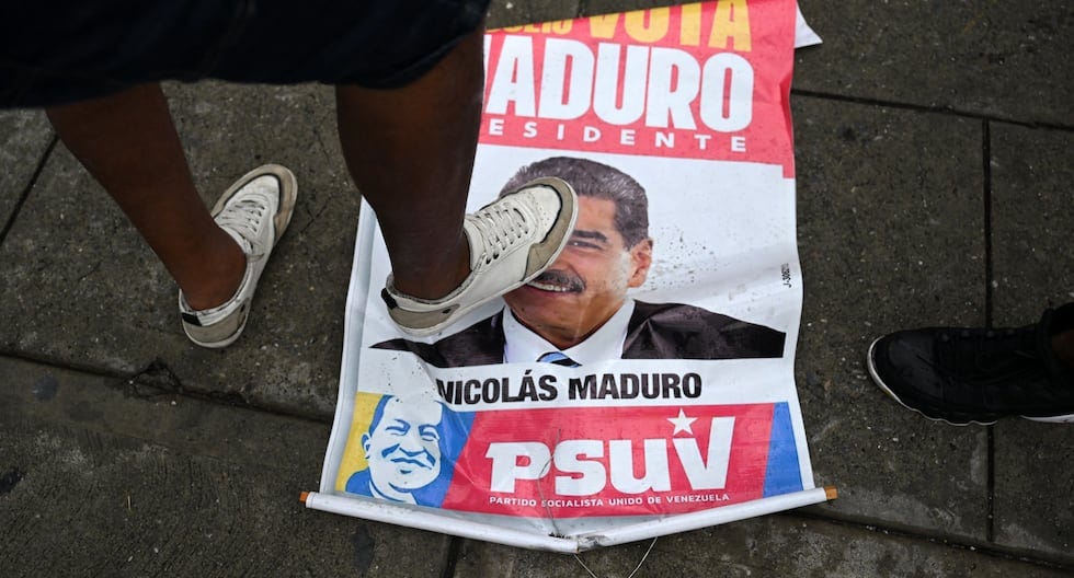 Un opositor al gobierno del presidente de Venezuela Nicolás Maduro pisa un cartel de campaña con su imagen durante una protesta en el barrio de Petare, en Caracas. (Foto de Raúl ARBOLEDA / AFP).