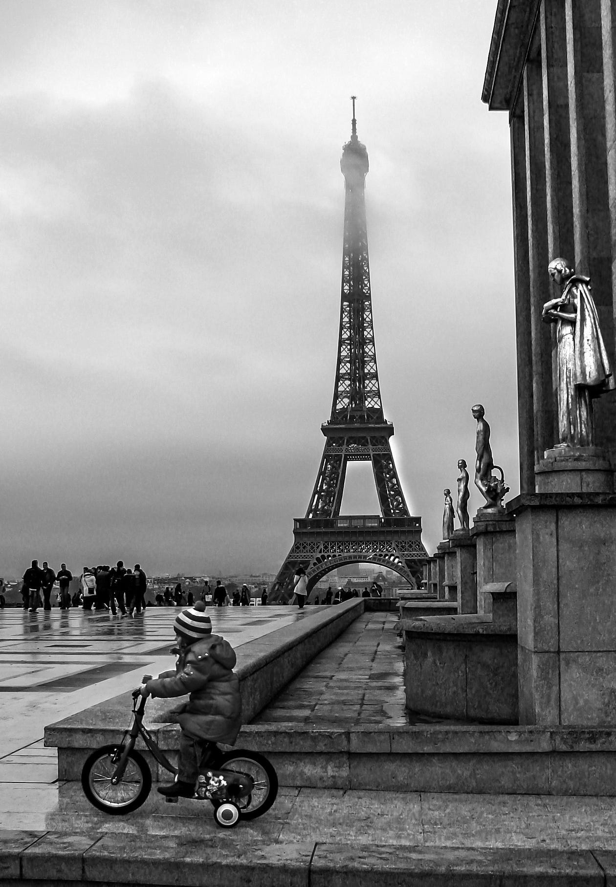 Girl riding bike with training wheels in Paris.