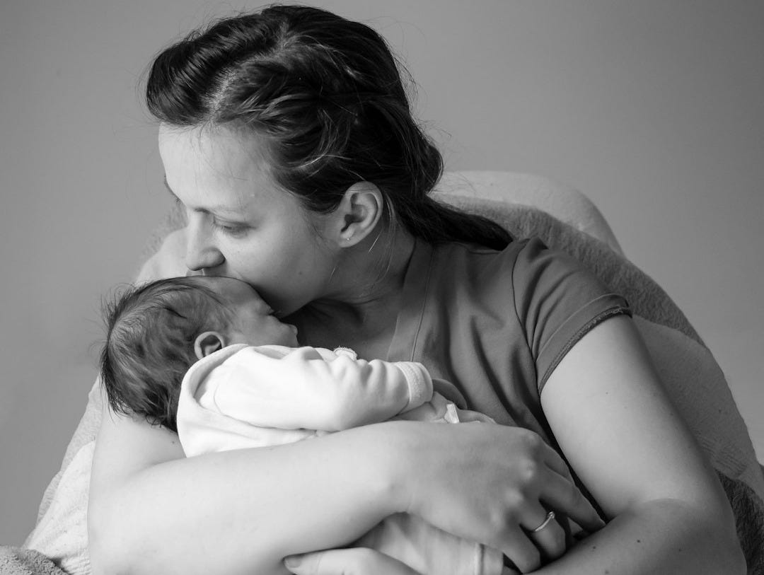 grayscale photo of woman in t-shirt carrying baby