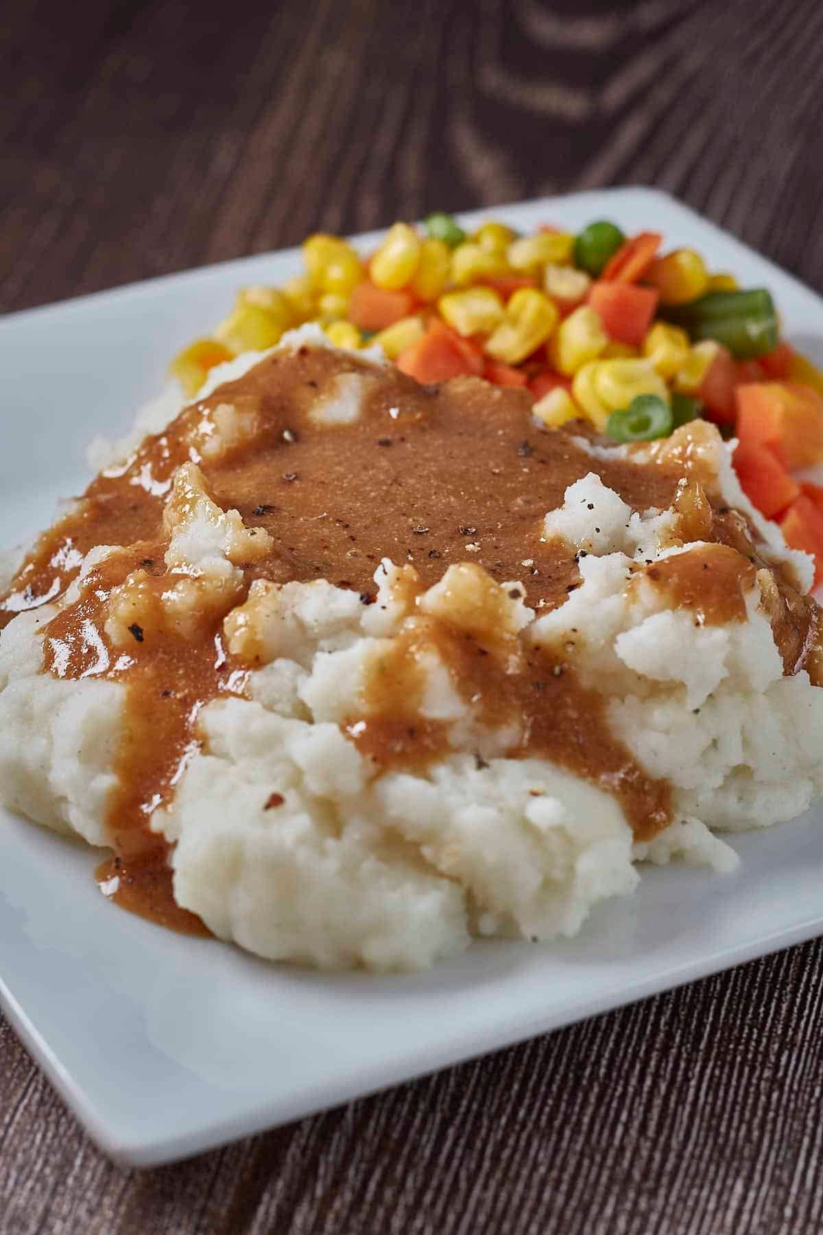 a plate of mashed potatoes covered in the best vegan gravy