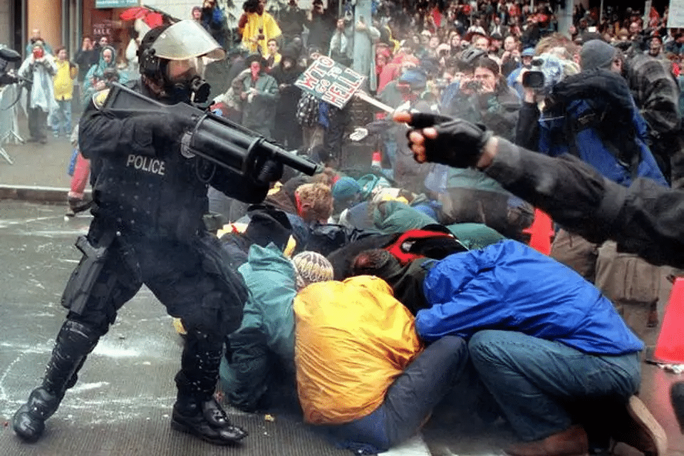 A person in a riot gear firing a sign

Description automatically generated