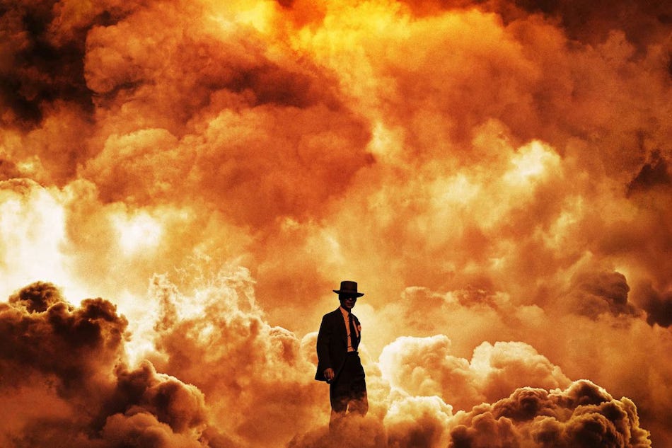 Uma pequena silhueta de homem magro de terno e chapéu está na frente de uma nuvem incandescente de explosão.
