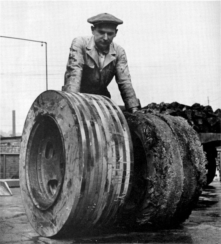 A mechanic shows off two pairs of hardwood tires—the pair on the left is new while the other has been driven 500 miles.