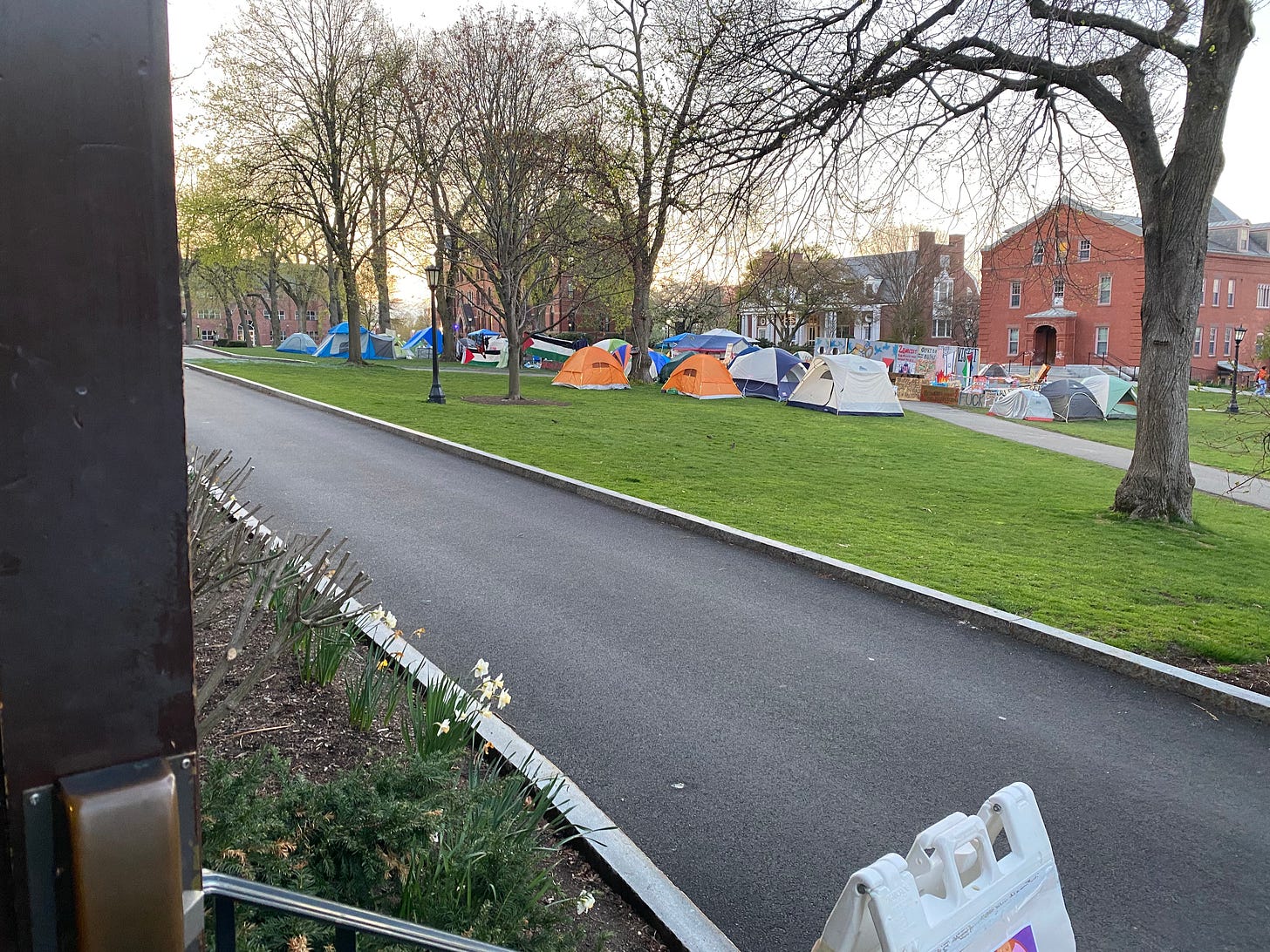 From the persepctive outside of a door, many colorful tents on a campus green area