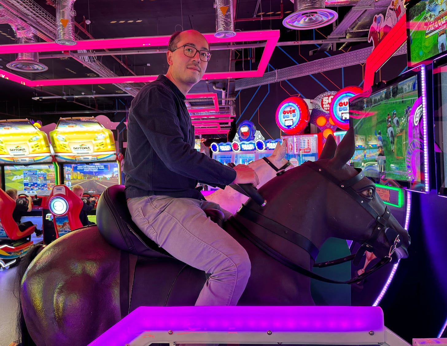 Adrian sitting on an arcade horse